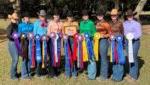 9 members of Western riding team standing with ribbons and plaque