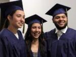3 smiling grads in caps and gowns